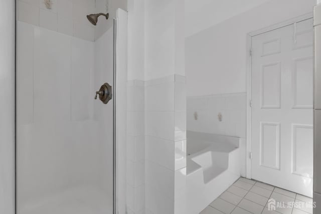 bathroom with tile patterned floors, tile walls, and independent shower and bath