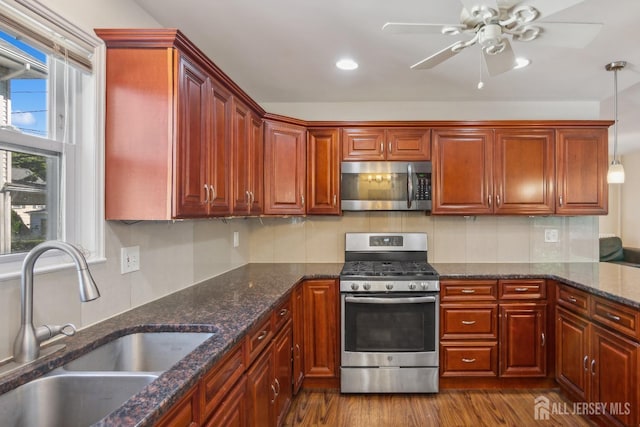 kitchen with pendant lighting, stainless steel appliances, tasteful backsplash, dark wood-type flooring, and a sink