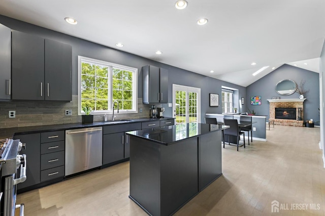 24 Saddle Ct, Monroe, NJ 08831 - kitchen with stainless steel appliances, a sink, dark countertops, a fireplace, and a kitchen island