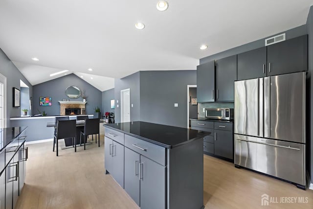 24 Saddle Ct, Monroe, NJ 08831 - kitchen featuring appliances with stainless steel finishes, dark countertops, light wood-type flooring, a kitchen island, and vaulted ceiling