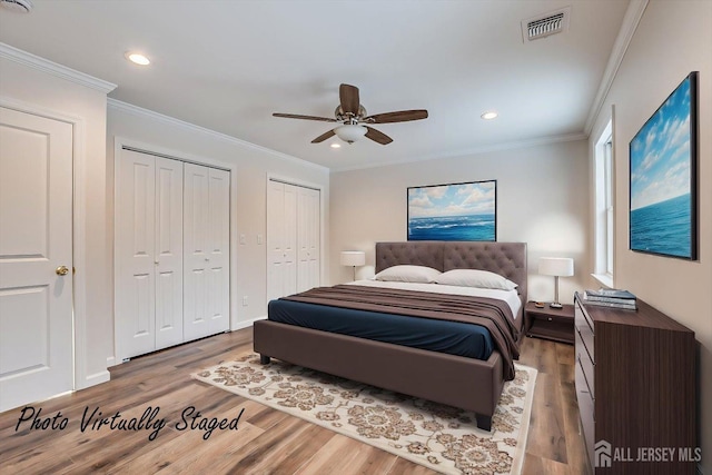 bedroom featuring multiple closets, crown molding, hardwood / wood-style floors, and ceiling fan