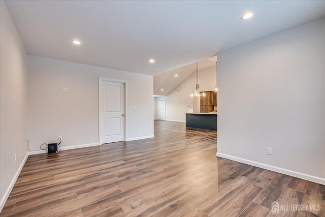 empty room with wood-type flooring and vaulted ceiling