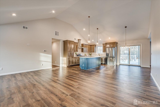 kitchen featuring hanging light fixtures, stainless steel appliances, dark hardwood / wood-style floors, a kitchen island, and wall chimney exhaust hood