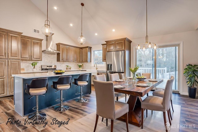 kitchen featuring backsplash, stainless steel appliances, wall chimney exhaust hood, and a kitchen island