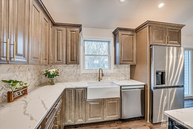 kitchen featuring light stone counters, sink, backsplash, and appliances with stainless steel finishes