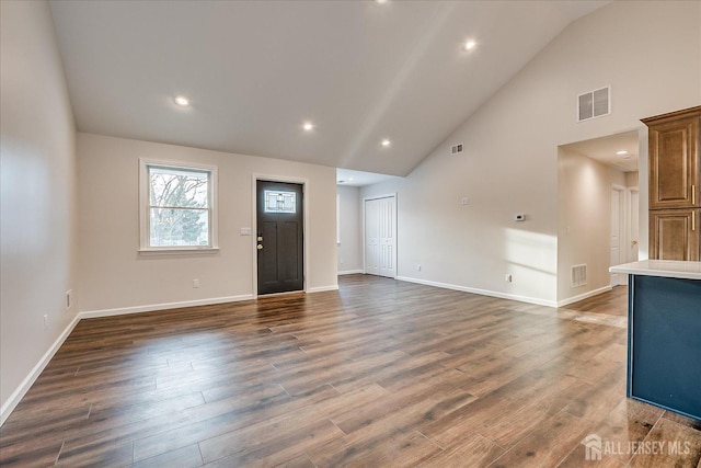 unfurnished living room featuring high vaulted ceiling and dark hardwood / wood-style floors