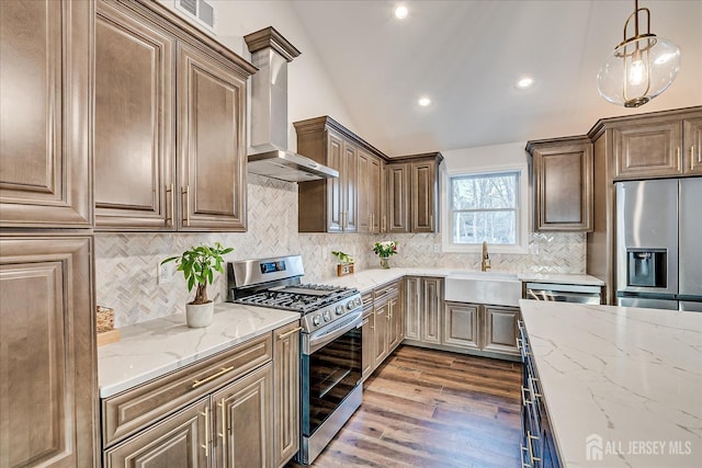 kitchen featuring sink, appliances with stainless steel finishes, light stone countertops, vaulted ceiling, and wall chimney exhaust hood