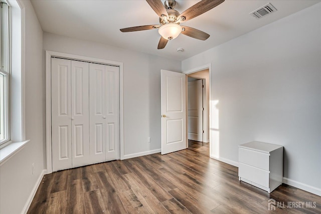 unfurnished bedroom with ceiling fan, dark hardwood / wood-style flooring, and a closet