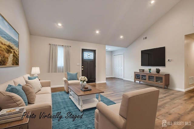 living room with hardwood / wood-style floors and high vaulted ceiling