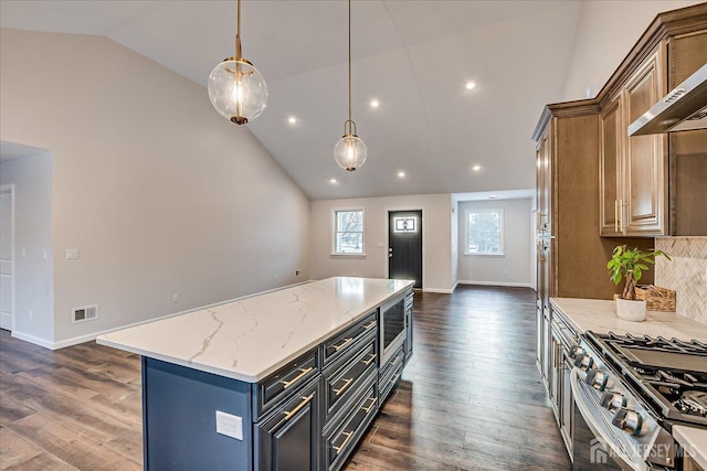 kitchen with pendant lighting, lofted ceiling, light stone counters, a kitchen island, and wall chimney exhaust hood