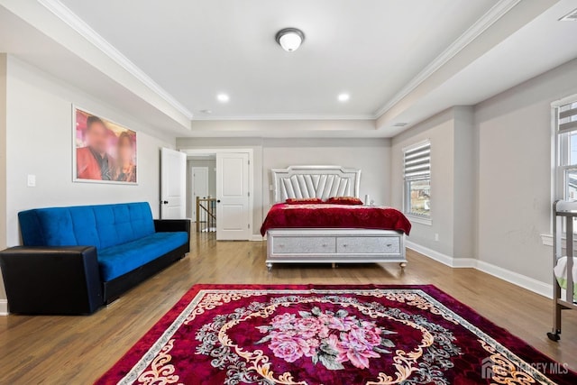 bedroom with a raised ceiling, wood finished floors, crown molding, baseboards, and recessed lighting