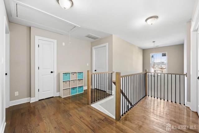 corridor with attic access, an upstairs landing, wood finished floors, and baseboards