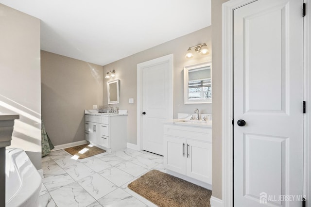 bathroom featuring marble finish flooring, two vanities, and baseboards