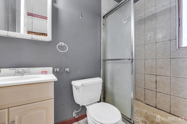 bathroom with vanity, toilet, and a shower with door