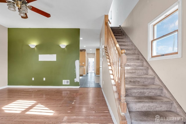 stairway featuring wood-type flooring and ceiling fan