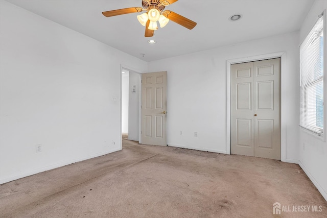 unfurnished bedroom with light carpet, a closet, and ceiling fan