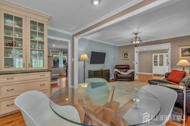 dining area with crown molding, a notable chandelier, and light hardwood / wood-style flooring