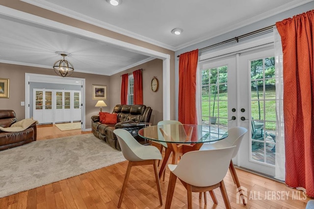 dining area featuring light hardwood / wood-style flooring, french doors, ornamental molding, and an inviting chandelier