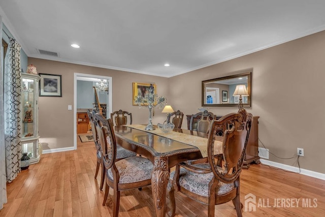 dining space with crown molding and light hardwood / wood-style floors