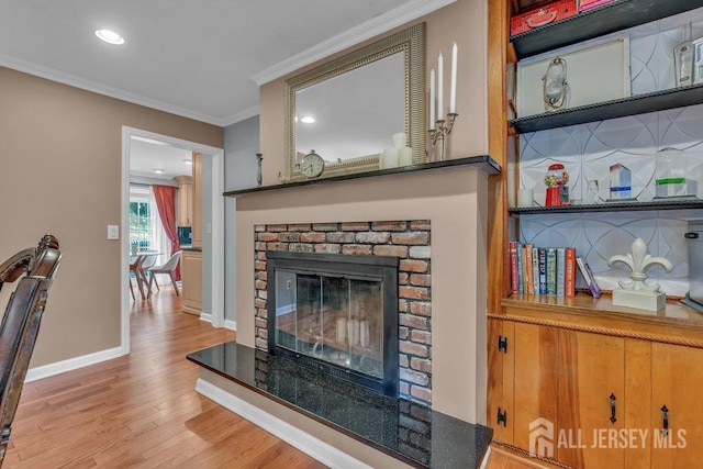 living room featuring light hardwood / wood-style floors, crown molding, and a fireplace