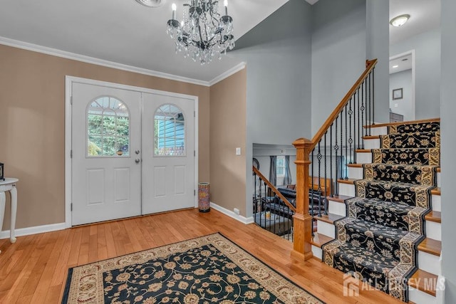 entrance foyer with crown molding, an inviting chandelier, and hardwood / wood-style floors