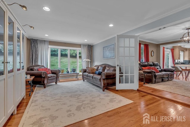 living room with french doors, crown molding, light hardwood / wood-style flooring, and a chandelier