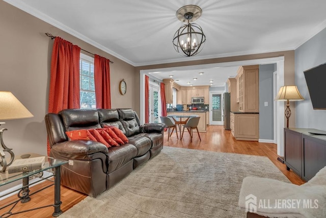 living room featuring a chandelier, crown molding, and light hardwood / wood-style floors