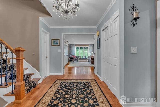 entryway featuring ornamental molding, a chandelier, and light wood-type flooring