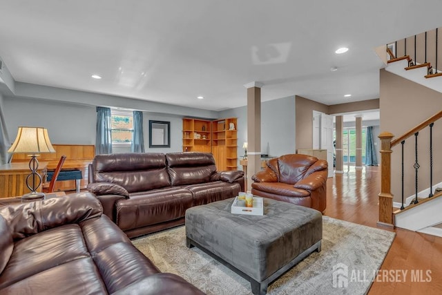 living room with a healthy amount of sunlight, decorative columns, and light hardwood / wood-style flooring