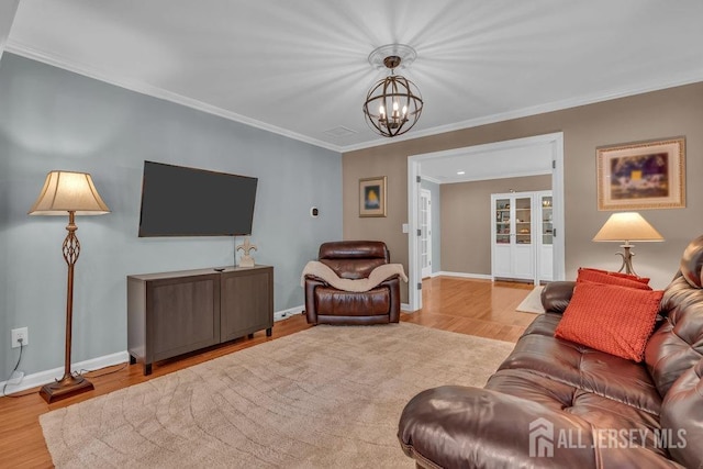 living room with light hardwood / wood-style flooring, a chandelier, and crown molding