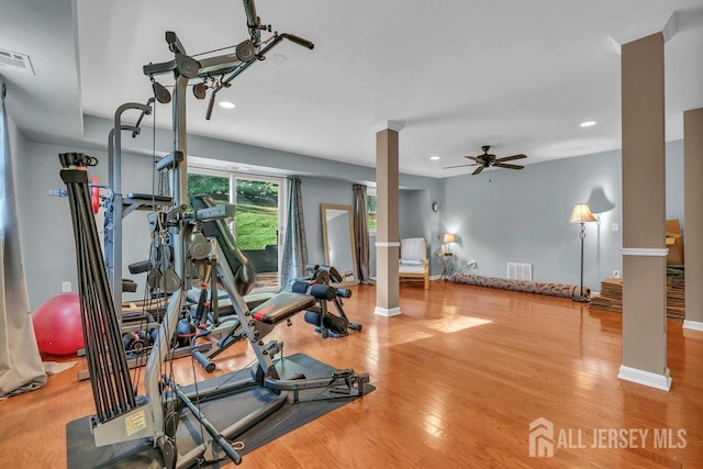 exercise room featuring hardwood / wood-style floors, ornate columns, and ceiling fan