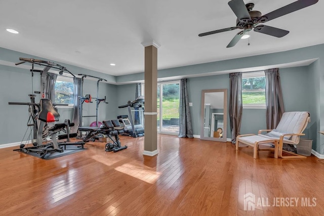 exercise area featuring decorative columns, light hardwood / wood-style flooring, and ceiling fan