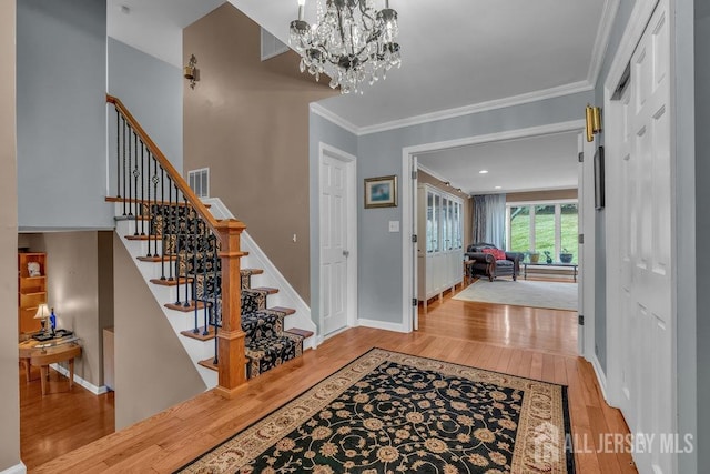 foyer featuring an inviting chandelier, crown molding, and light wood-type flooring