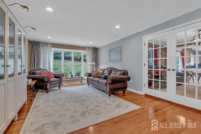 living room with french doors, crown molding, and light wood-type flooring