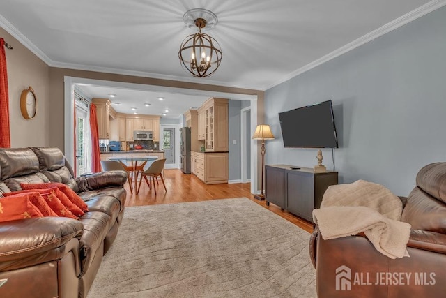 living room featuring a notable chandelier, ornamental molding, and light wood-type flooring