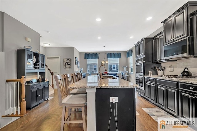 1501 Hights Farm Rd Unit 1501, Monroe, NJ 08831 - kitchen featuring a sink, dark cabinetry, a kitchen island with sink, light wood-style floors, and recessed lighting