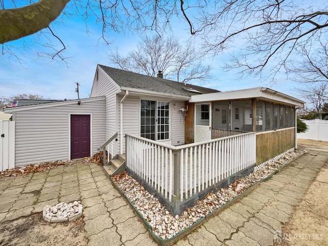 view of front of house featuring a chimney, a sunroom, and fence