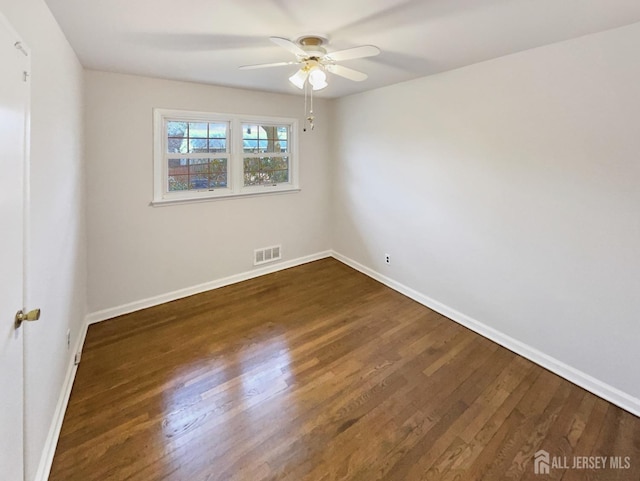 spare room featuring visible vents, dark wood-style flooring, and baseboards