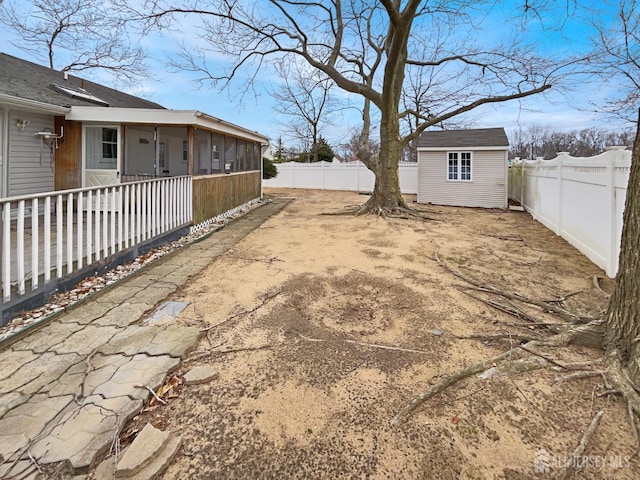 view of yard featuring an outbuilding, a fenced backyard, and a sunroom