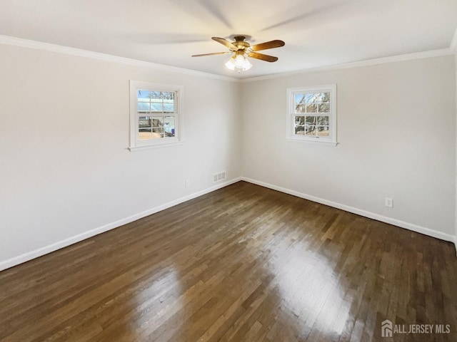 unfurnished room with visible vents, plenty of natural light, dark wood finished floors, and ornamental molding