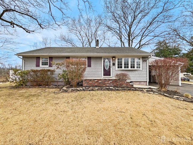 ranch-style house with brick siding, a chimney, and a front yard