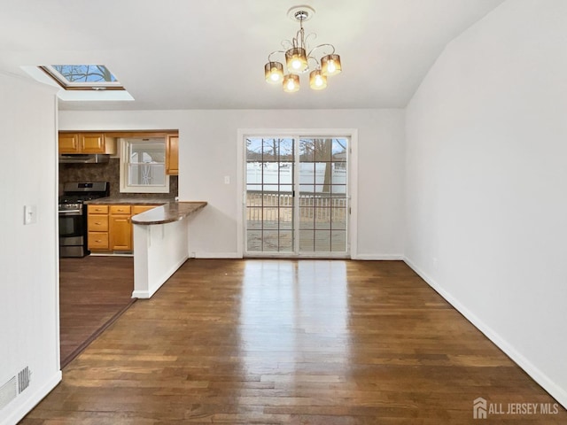 unfurnished dining area with visible vents, dark wood-style floors, vaulted ceiling with skylight, baseboards, and a chandelier