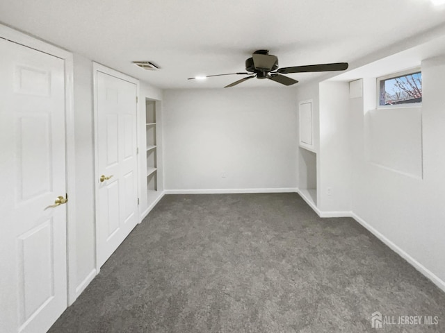 unfurnished bedroom with baseboards, visible vents, dark carpet, and ceiling fan