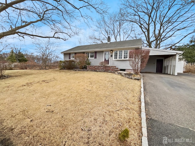 ranch-style house featuring aphalt driveway, a carport, a front lawn, and a chimney