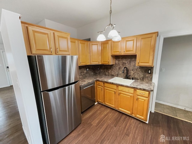 kitchen with dark wood-style flooring, a sink, appliances with stainless steel finishes, dark countertops, and tasteful backsplash