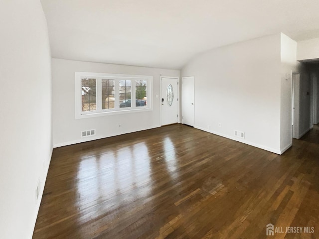 unfurnished living room with dark wood-style floors, visible vents, and vaulted ceiling