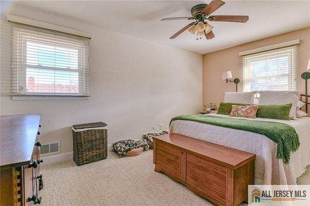 carpeted bedroom with a ceiling fan, visible vents, and baseboards