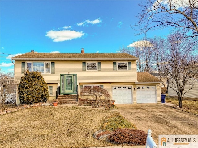 bi-level home featuring concrete driveway, a chimney, and a front yard