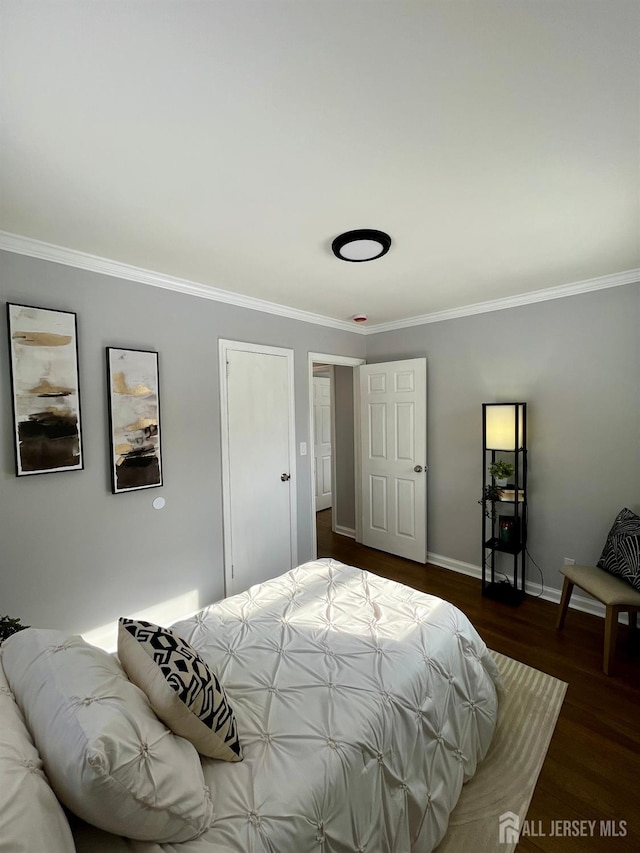 bedroom with baseboards, wood finished floors, and crown molding