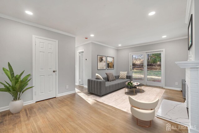 living room featuring a brick fireplace, light wood-type flooring, and ornamental molding